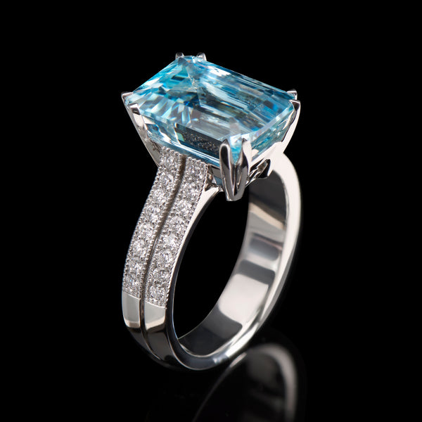 A step-cut aquamarine single stone ring with diamond set shoulders