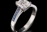 An exceptional emerald cut diamond single stone ring with sapphire shoulders
