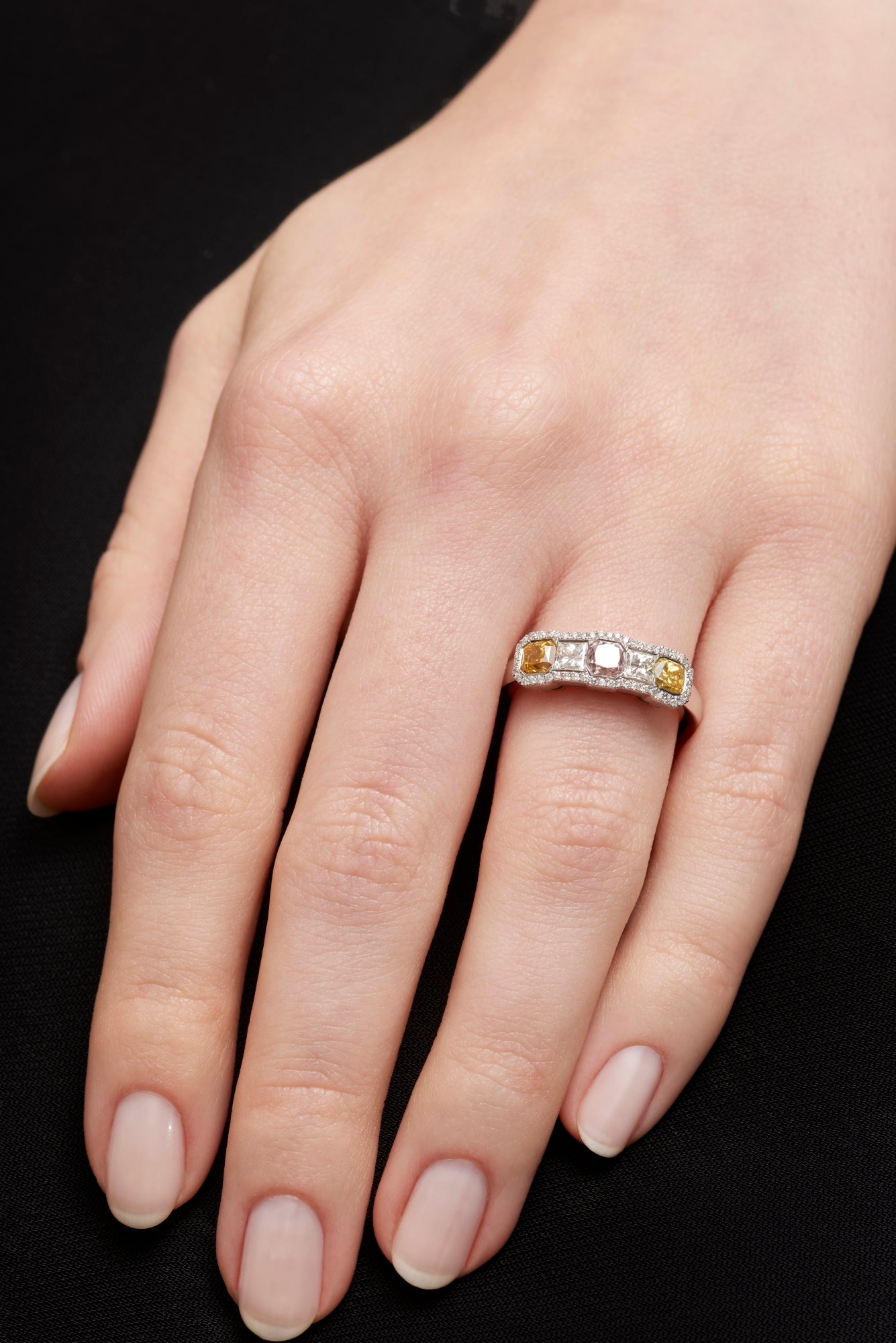 An all diamond half hoop ring with three fancy natural colour diamonds.