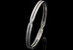 A diamond cross over bangle in platinum