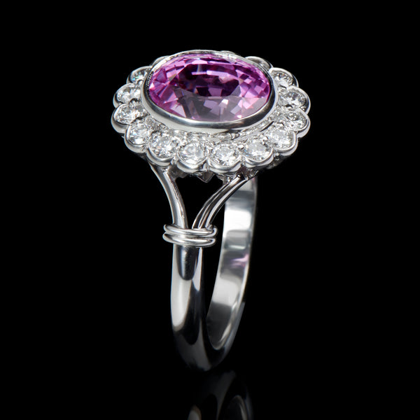 An oval pink sapphire & diamond cluster ring with split shoulders