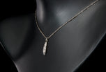 A diamond five stone tonneau baton pendant